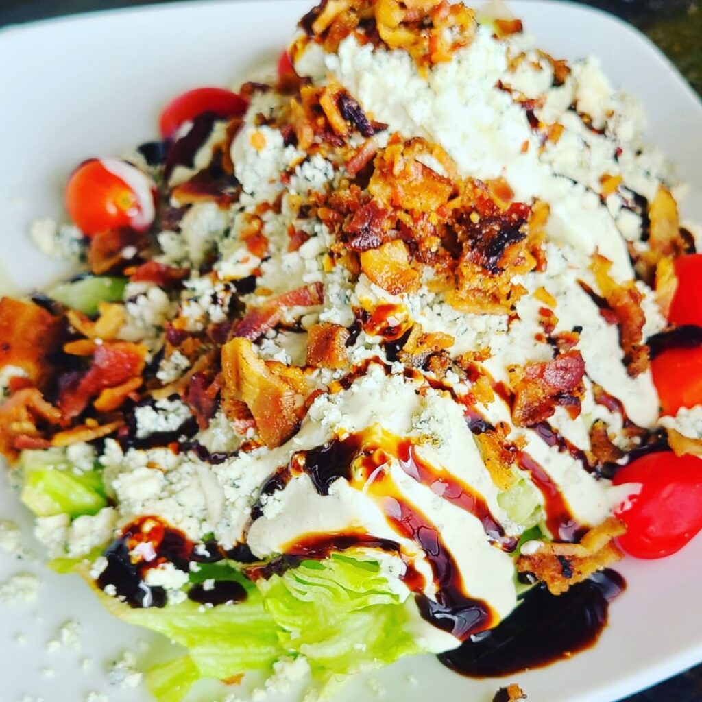wedge salad with blue cheese bacon bits and balsamic drizzle