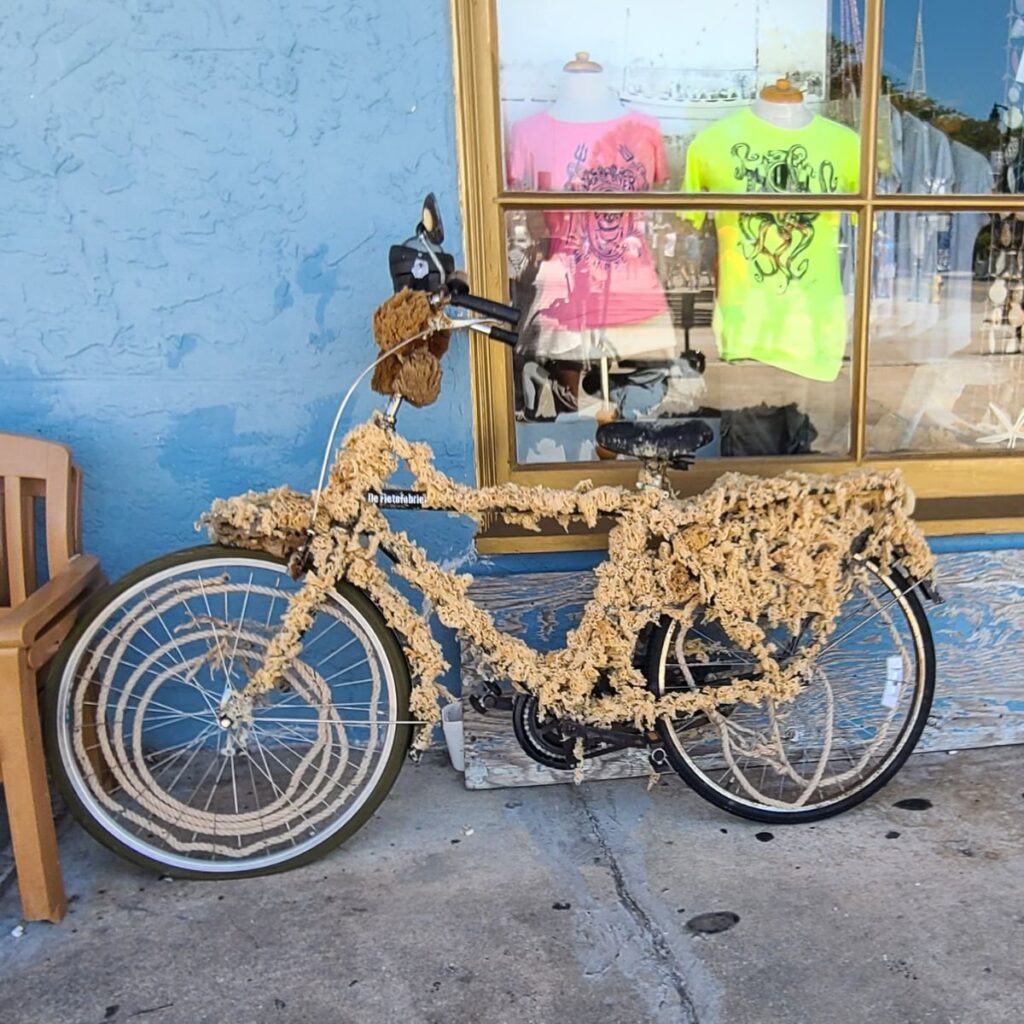 bicycle covered in dried sponges on display in front of a boutique shop in tarpon springs